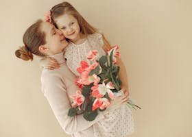 A joyful moment of a mother and daughter embracing with a bouquet of tulips in hand.