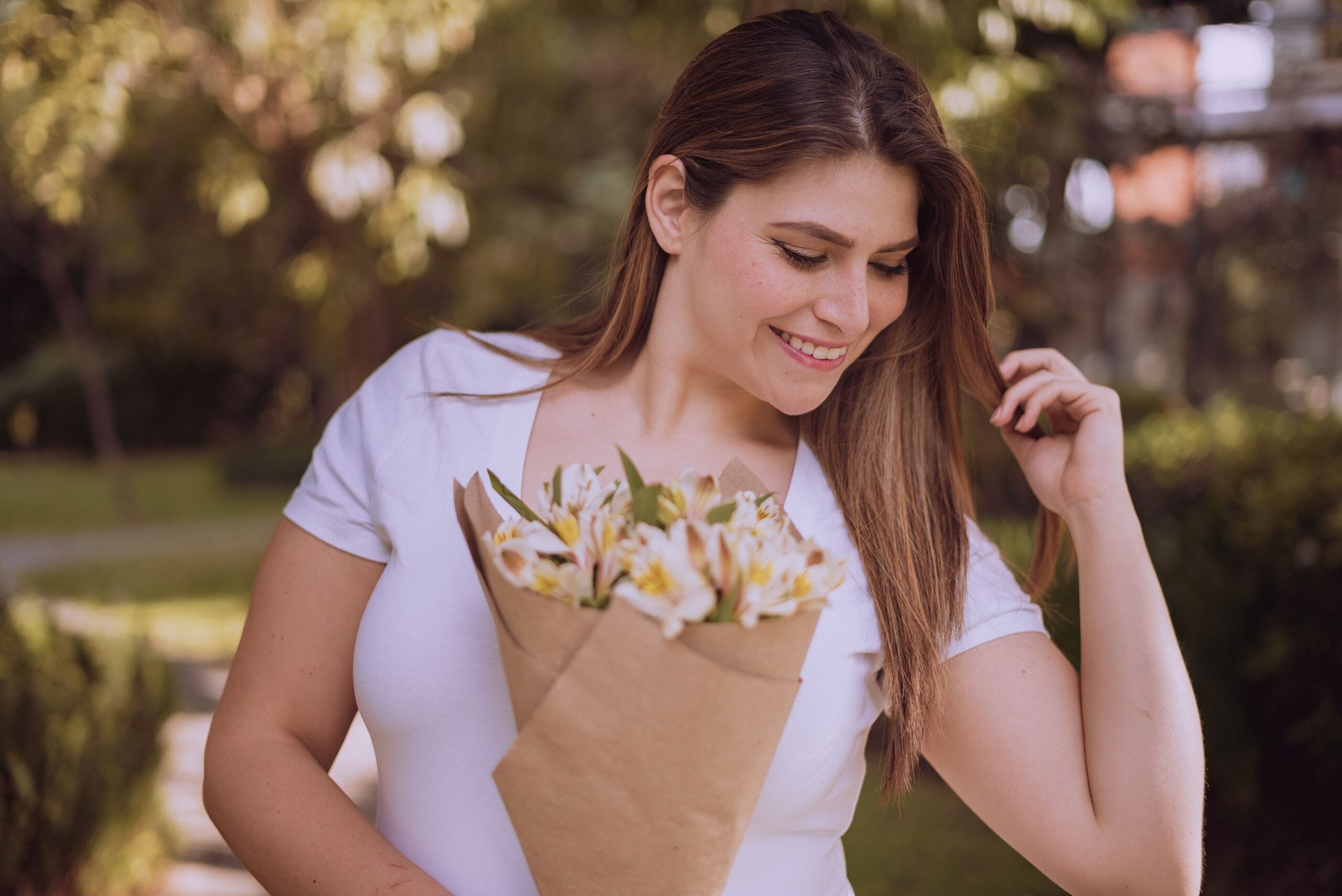 Happy woman with a bouquet of flowers, enjoying a sunny day outside.